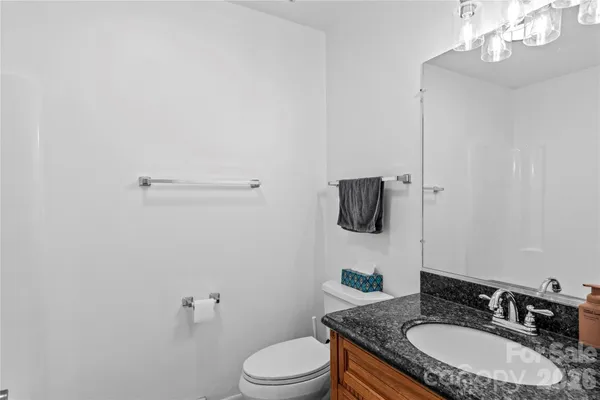 a bathroom with a granite countertop sink a toilet and mirror
