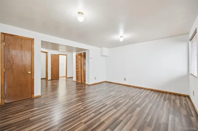 a view of an empty room with wooden floor and closet