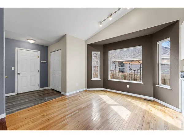 a view of an empty room with window and wooden floor