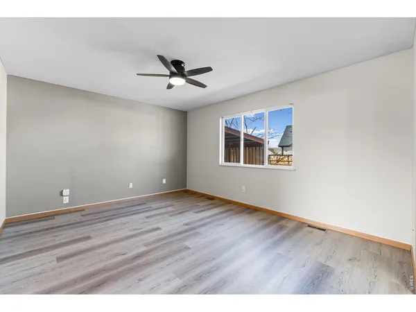 a view of an empty room with a window and wooden floor