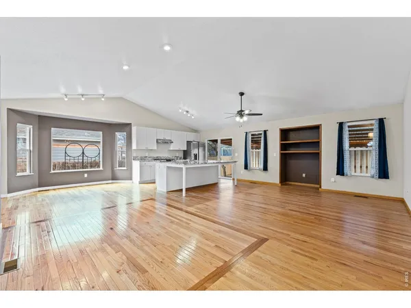 a view of an empty room with wooden floor and a fireplace