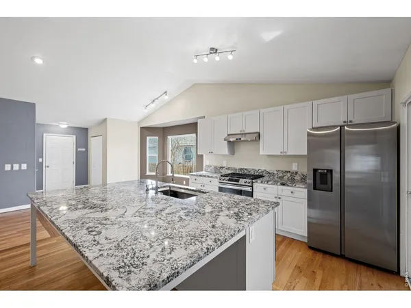 a kitchen with stainless steel appliances granite countertop a sink refrigerator and cabinets