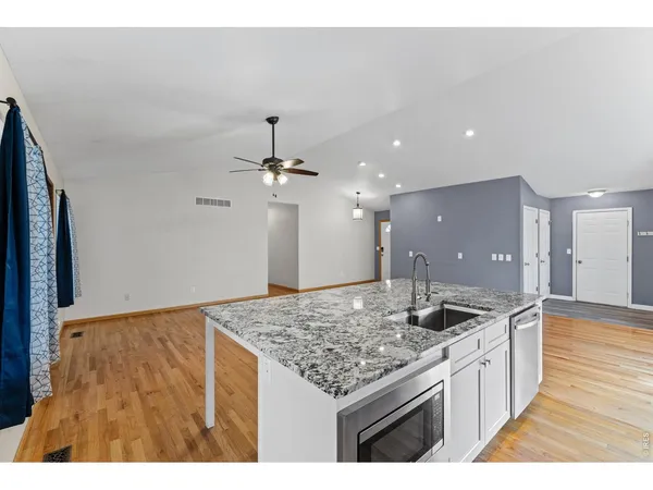 a kitchen with kitchen island granite countertop a sink and refrigerator