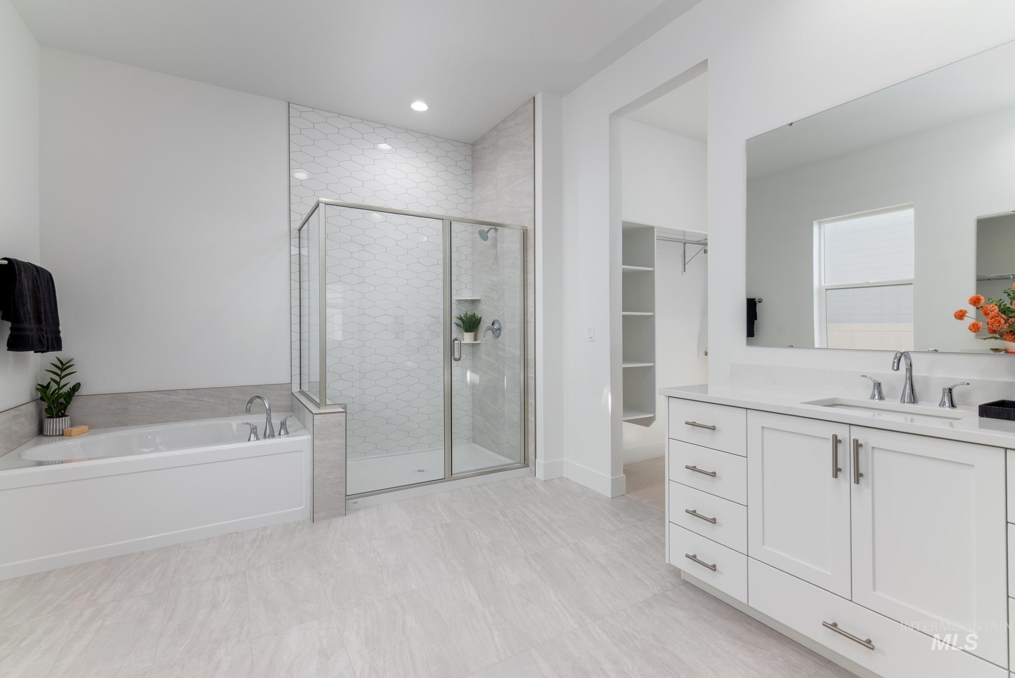 9074 West Moonglade Street Star, ID 83669 - Photo 21 of 40 Spacious bathroom featuring a white soaking tub, separate glass-enclosed shower with hexagonal tile, a single vanity with stone countertop, and light-toned tile flooring