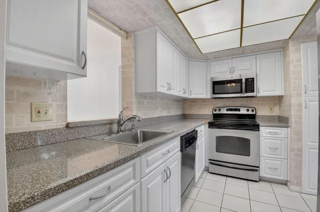 a kitchen with granite countertop white cabinets stainless steel appliances and a sink