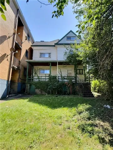 a view of a house next to a big yard and large trees