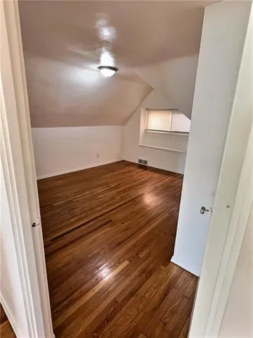 a view of an empty room with wooden floor and stairs