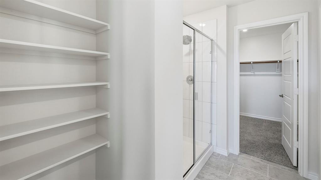 403 Flintlock Road Caddo Mills, TX 75135 - Photo 6 of 26 Bathroom featuring a walk in closet, a shower stall, and light tile patterned floors