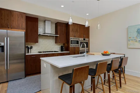 a kitchen with stainless steel appliances a dining table chairs refrigerator and sink