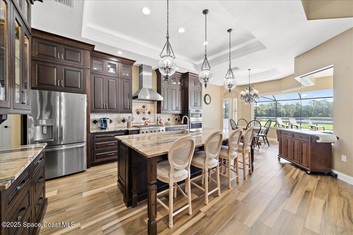 4464 Preservation Circle Melbourne, FL 32934 - Photo 7 of 65 a kitchen with stainless steel appliances kitchen island granite countertop a table chairs and a chandelier