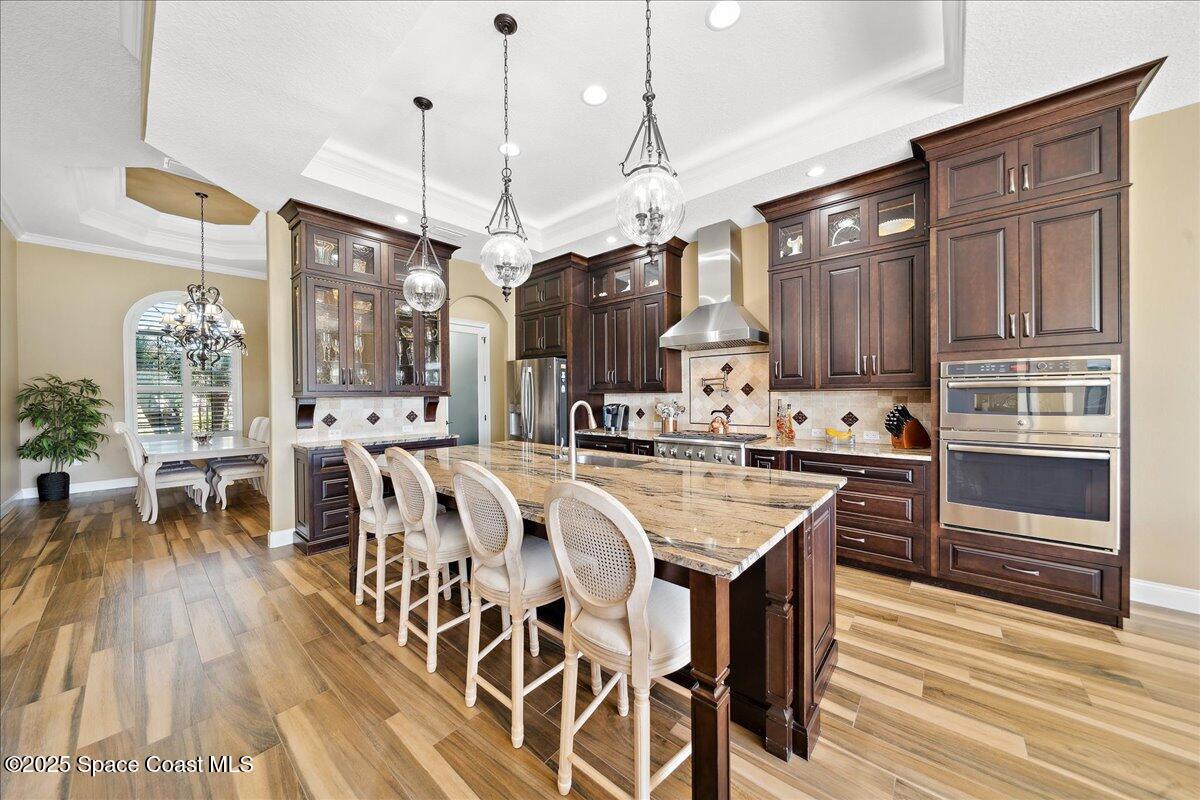4464 Preservation Circle Melbourne, FL 32934 - Photo 9 of 65 a open kitchen with stainless steel appliances granite countertop a kitchen island a stove a refrigerator a oven a dining table and chairs with wooden floor