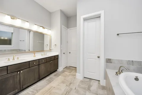 a bathroom with a tub a sink and mirror