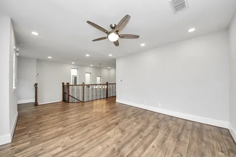 a view of an empty room with window and wooden floor