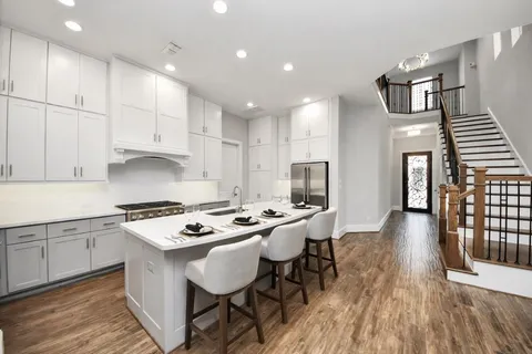 a kitchen that has a table chairs in it wooden floors and white cabinets