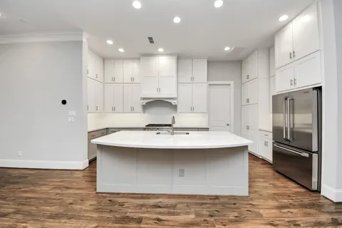 a view of a kitchen with kitchen island a sink stainless steel appliances and cabinets
