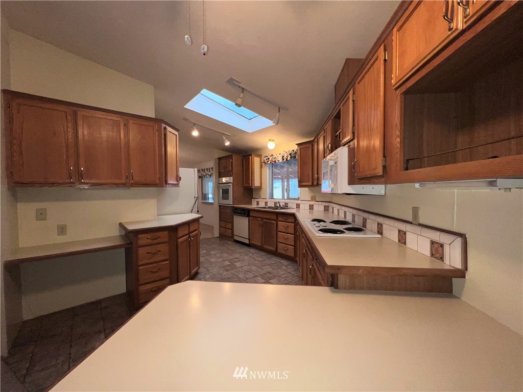 1009 Fir Loop Republic, WA 99166 - Photo 9 of 30 a kitchen with stainless steel appliances granite countertop a sink dishwasher stove and a microwave oven with cabinets