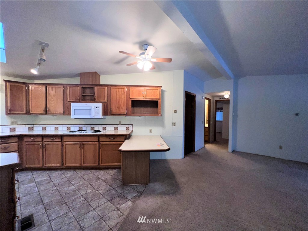 1009 Fir Loop Republic, WA 99166 - Photo 10 of 30 a large white kitchen with a sink a stove a kitchen island with chairs and granite counter