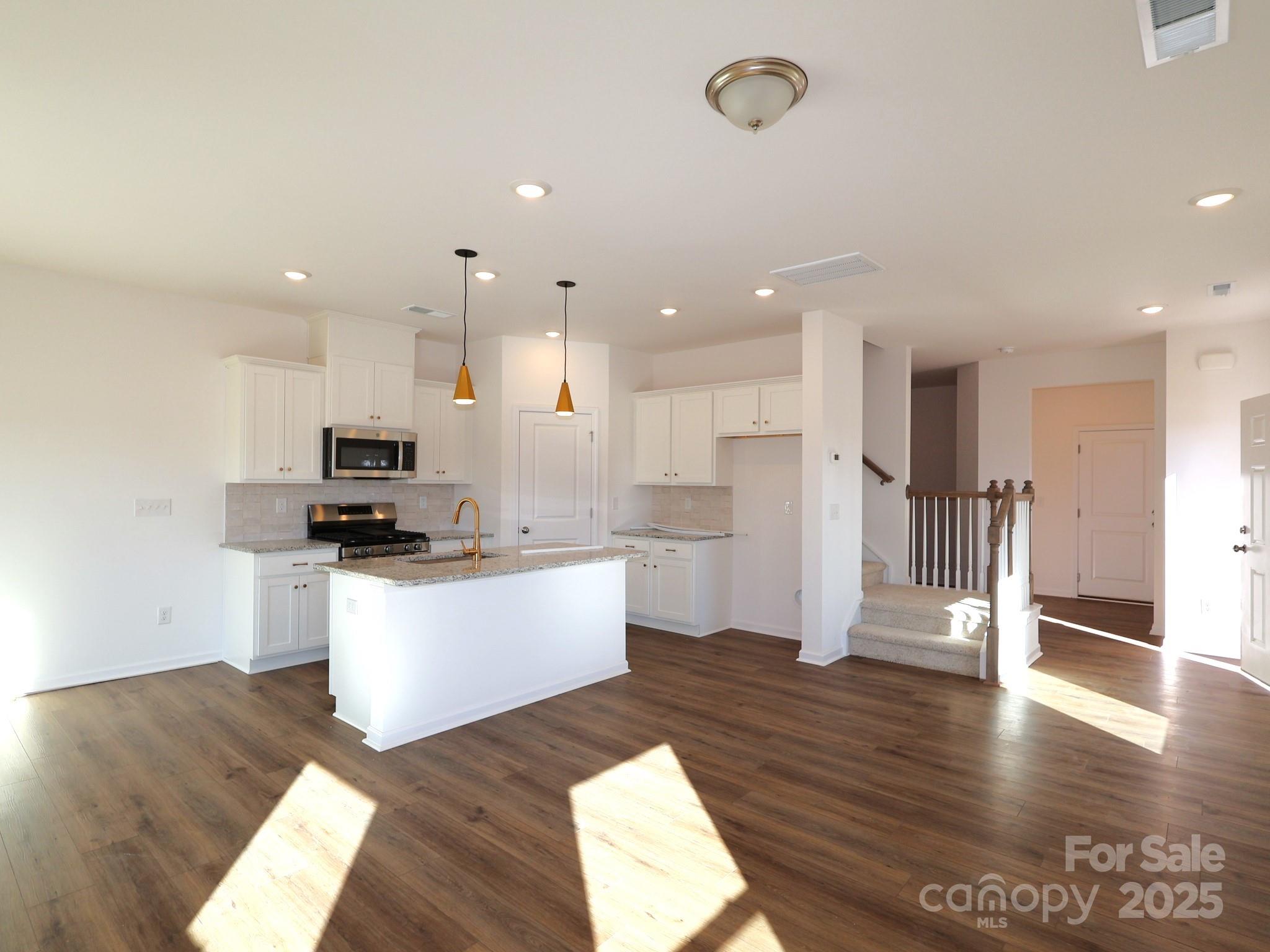 776 Kitfox Drive Northwest Concord, NC 28027 - Photo 4 of 12 a kitchen with stainless steel appliances kitchen island granite countertop a refrigerator a sink a stove and white cabinets with wooden floor