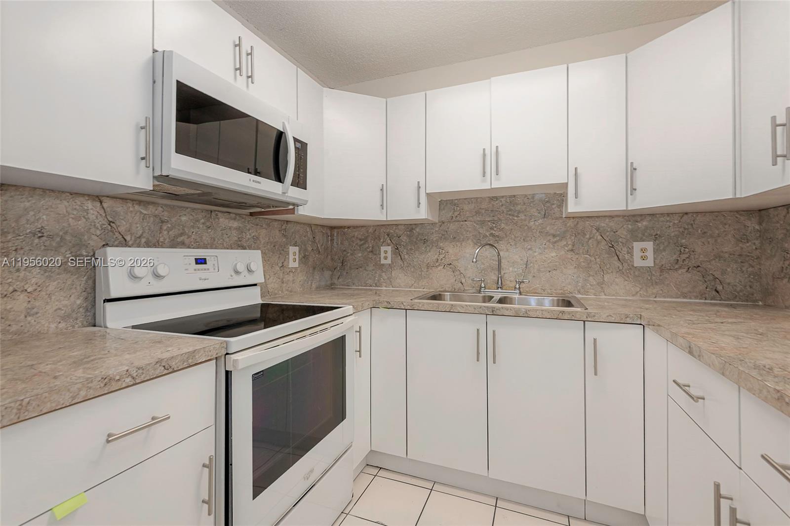 7785 West 30th Court, Unit F104 Hialeah, FL 33018 - Photo 4 of 17 a kitchen with granite countertop white cabinets stainless steel appliances and a sink