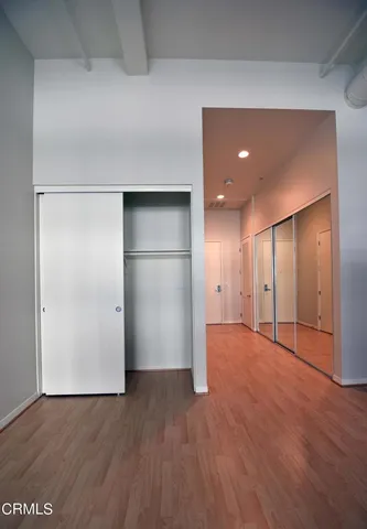 a view of an empty room with wooden floor and closet