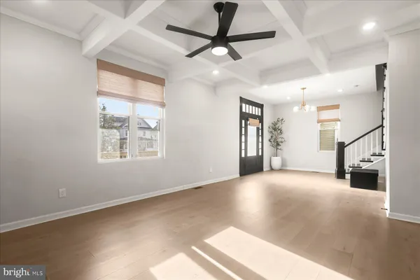 an empty room with chandelier fan and windows