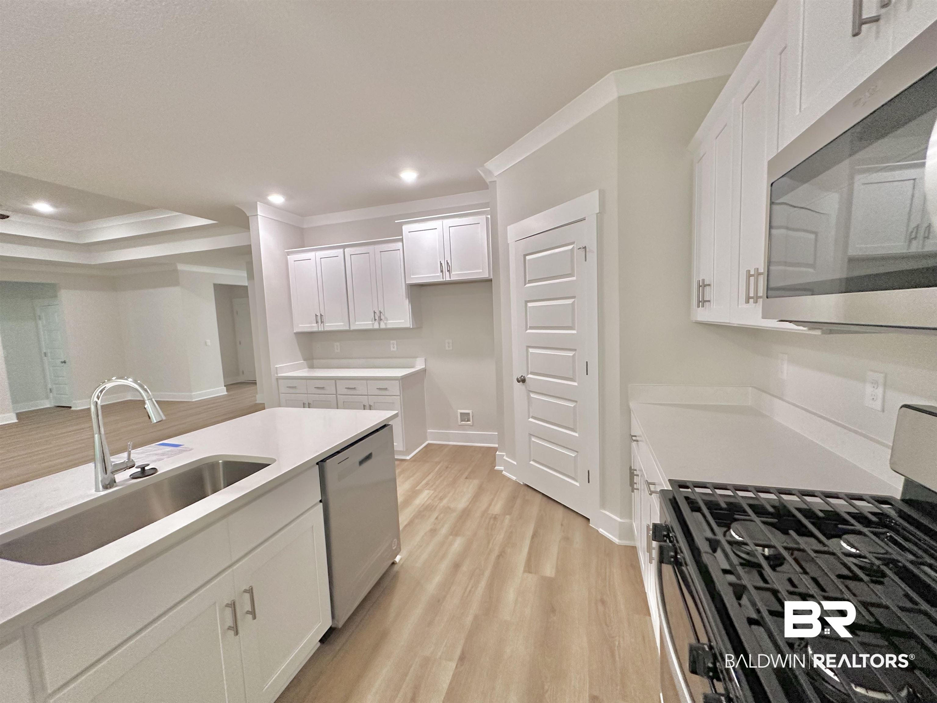 342 Barndling Street Fairhope, AL 36532 - Photo 9 of 50 Kitchen with ornamental molding, appliances with stainless steel finishes, sink, white cabinets, and light hardwood / wood-style flooring