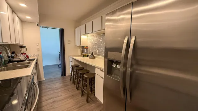 a kitchen with kitchen island a counter top space a sink stainless steel appliances and cabinets