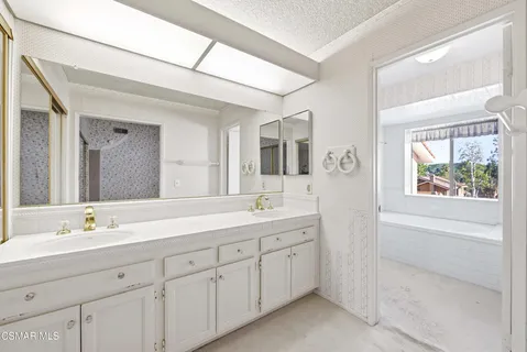 a bathroom with a double vanity sink and mirror with bathtub