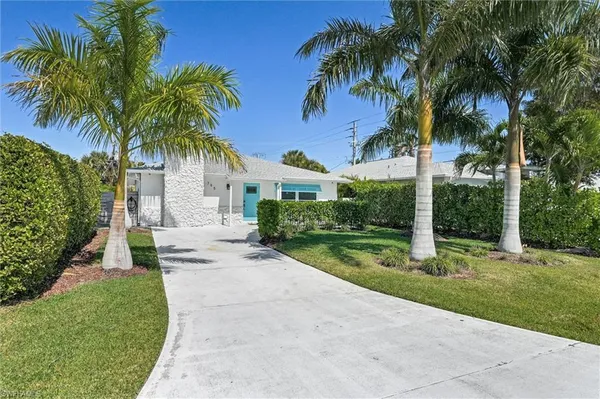 a view of a house with a yard and palm trees