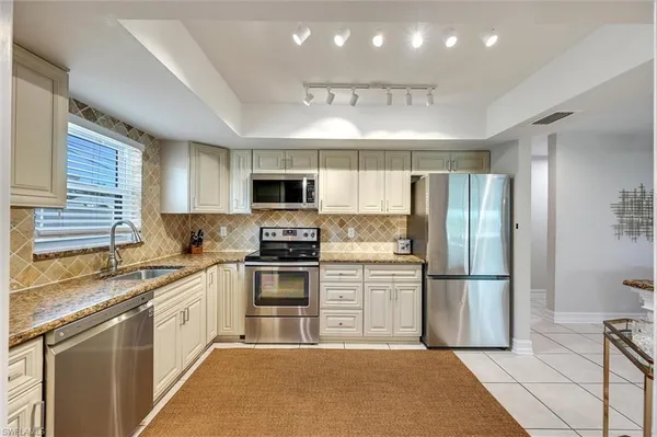 a kitchen with a sink a refrigerator and cabinets