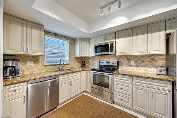 a kitchen with cabinets stainless steel appliances a sink and a window