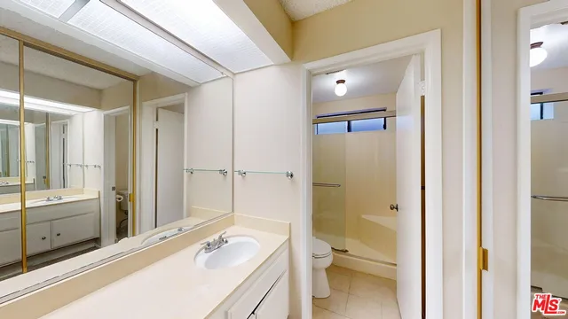 a bathroom with a granite countertop sink a toilet and shower