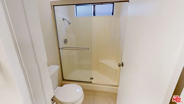 a white toilet sitting next to a shower