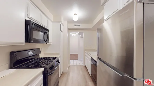 a kitchen with granite countertop a refrigerator stove and sink