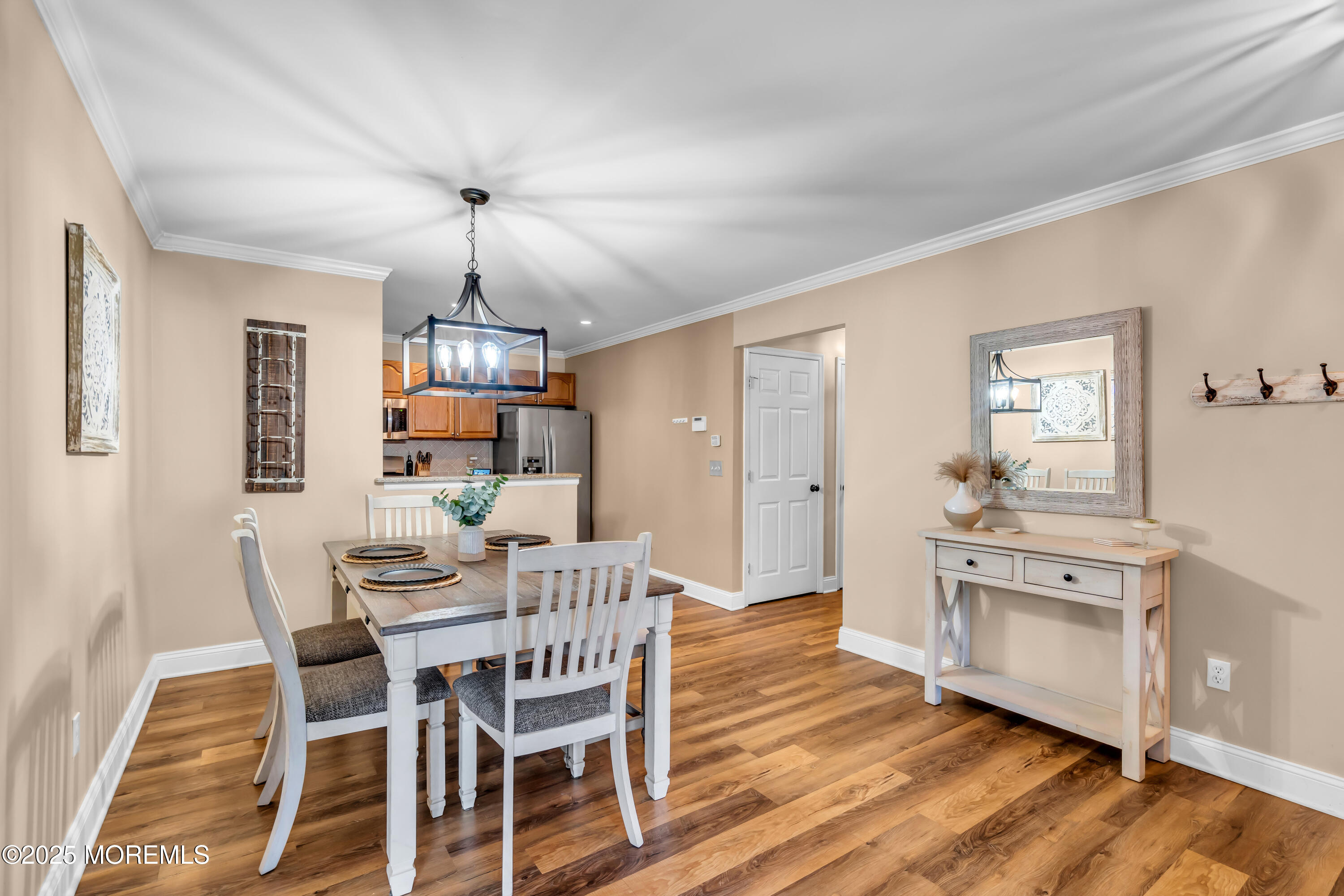 455 Deuce Drive Wall, NJ 07719 - Photo 6 of 26 a dining room with wooden floor a chandelier a wooden table and chairs