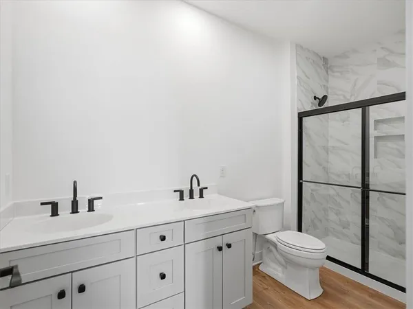 a bathroom with a toilet a sink a mirror and shower