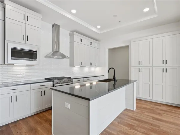 a kitchen with kitchen island a sink stainless steel appliances white cabinets and wooden floor