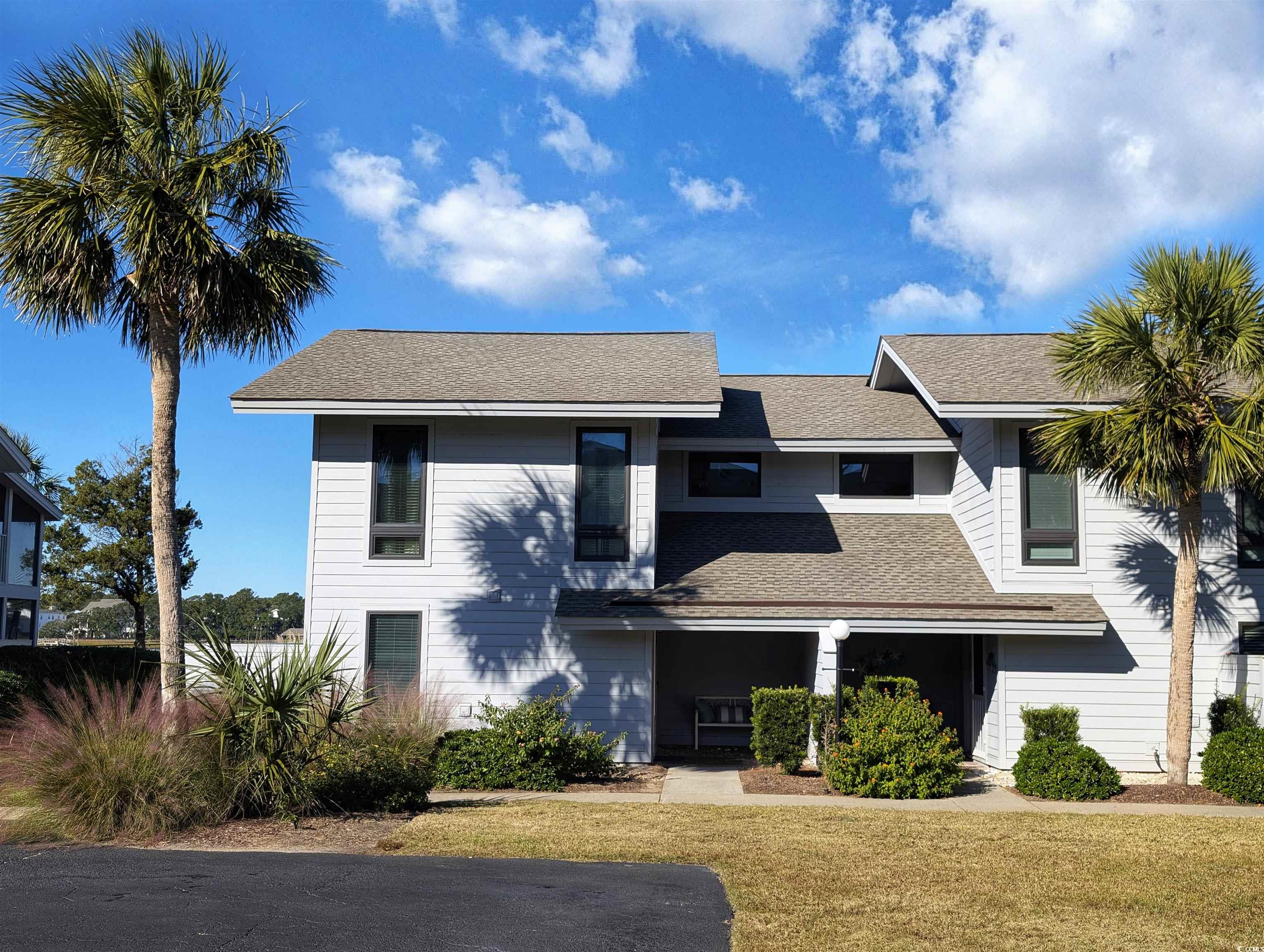 View of front of house featuring a shingled roof and a front lawn