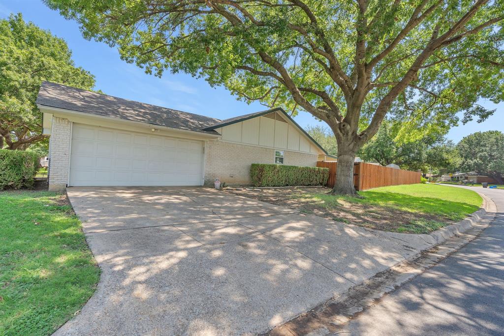 1720 Timbercreek Road Benbrook, TX 76126 - Photo 30 of 33 Exterior featuring a light brick façade, two-car garage, concrete driveway, and mature trees providing shade