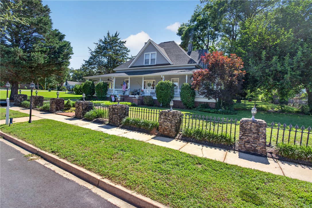 110 South Fairplay Street Seneca, SC 29678 - Photo 4 of 50 A charming residence welcomes with a wide front porch and a distinctive stone and wrought iron fence.