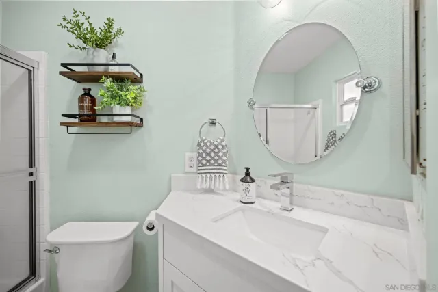 a front view of a dining room with furniture one side kitchen view and windows