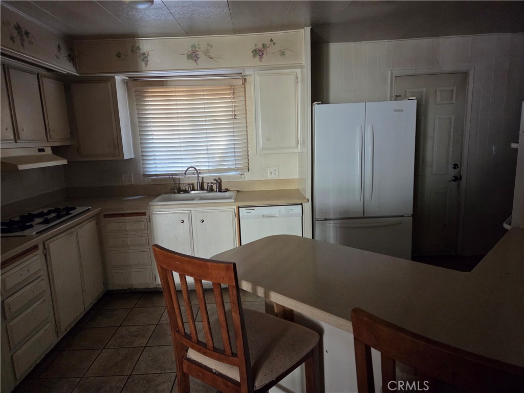 22899 Byron Road, Unit 41 Crestline, CA 92325 - Photo 4 of 10 a kitchen with stainless steel appliances granite countertop a table chairs sink refrigerator and microwave