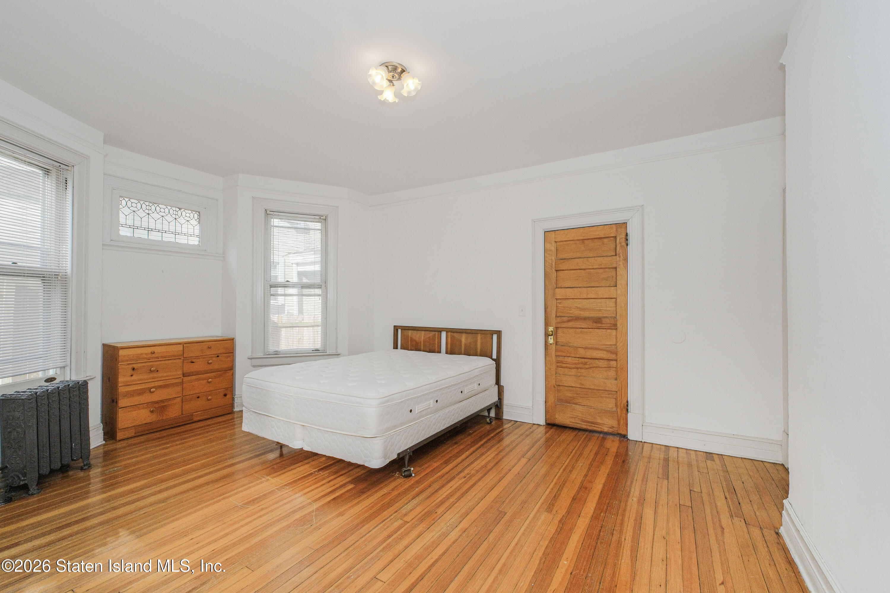 98 Hamilton Avenue Staten Island, NY 10301 - Photo 14 of 55 a bedroom with a bed and wooden floor