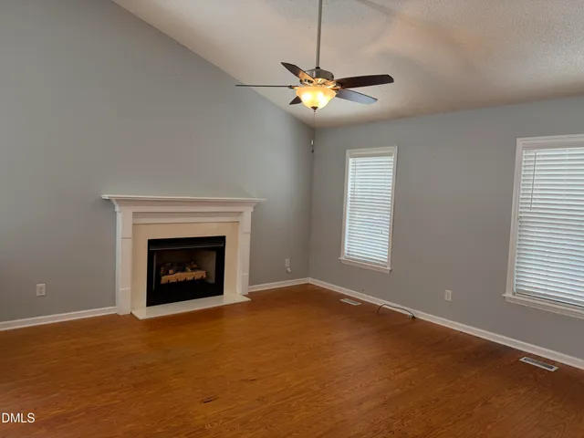 a view of an empty room with window and chandelier fan