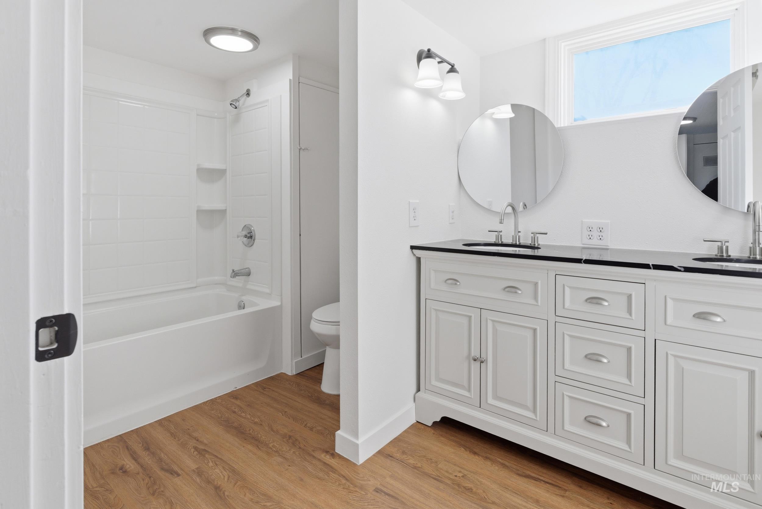 107 West Main Street Declo, ID 83323 - Photo 18 of 32 Bathroom featuring double vanity, light wood-type flooring, and bathtub / shower combination