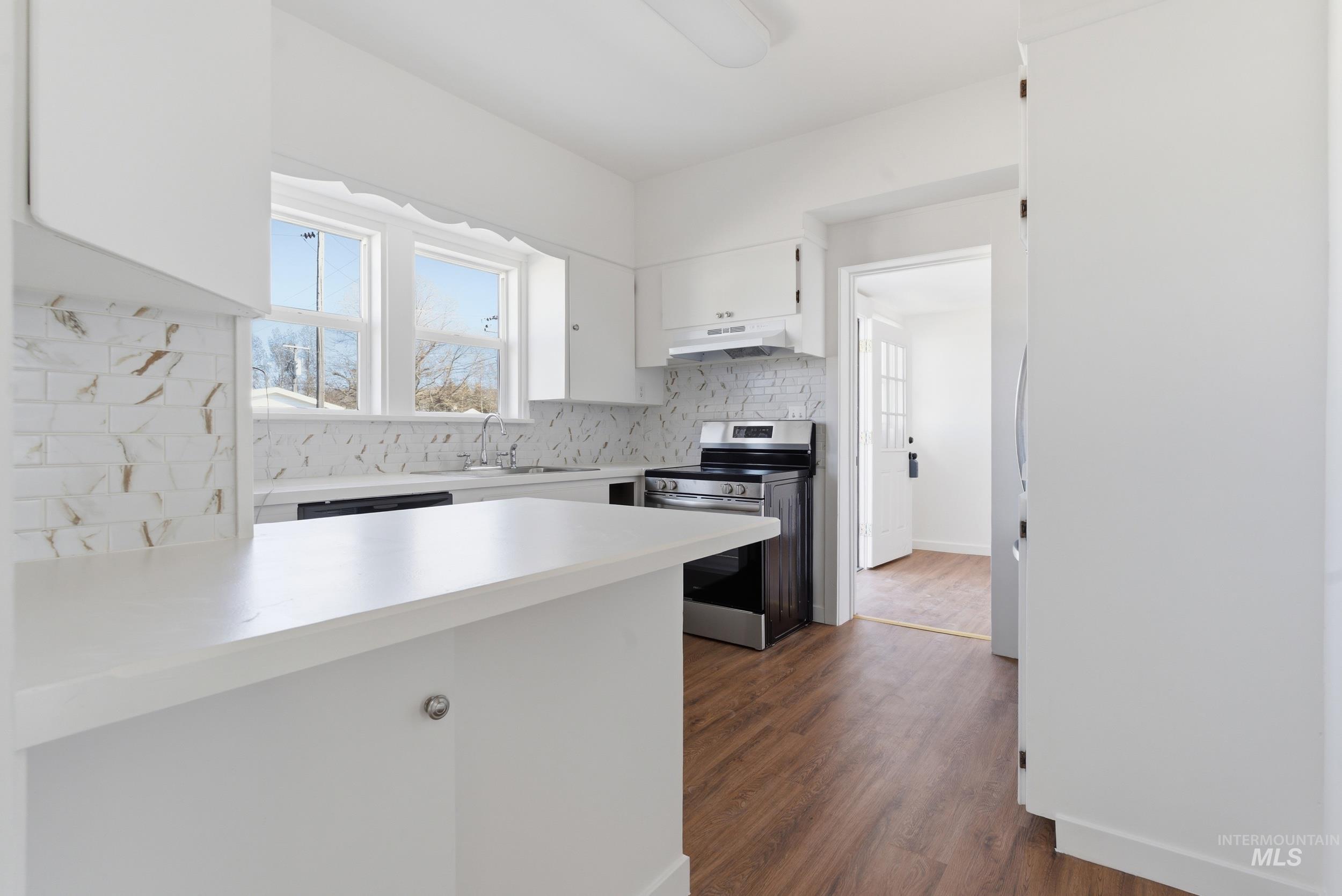 107 West Main Street Declo, ID 83323 - Photo 2 of 32 Kitchen featuring white cabinets, light countertops, electric stove, dark wood-style flooring, and backsplash