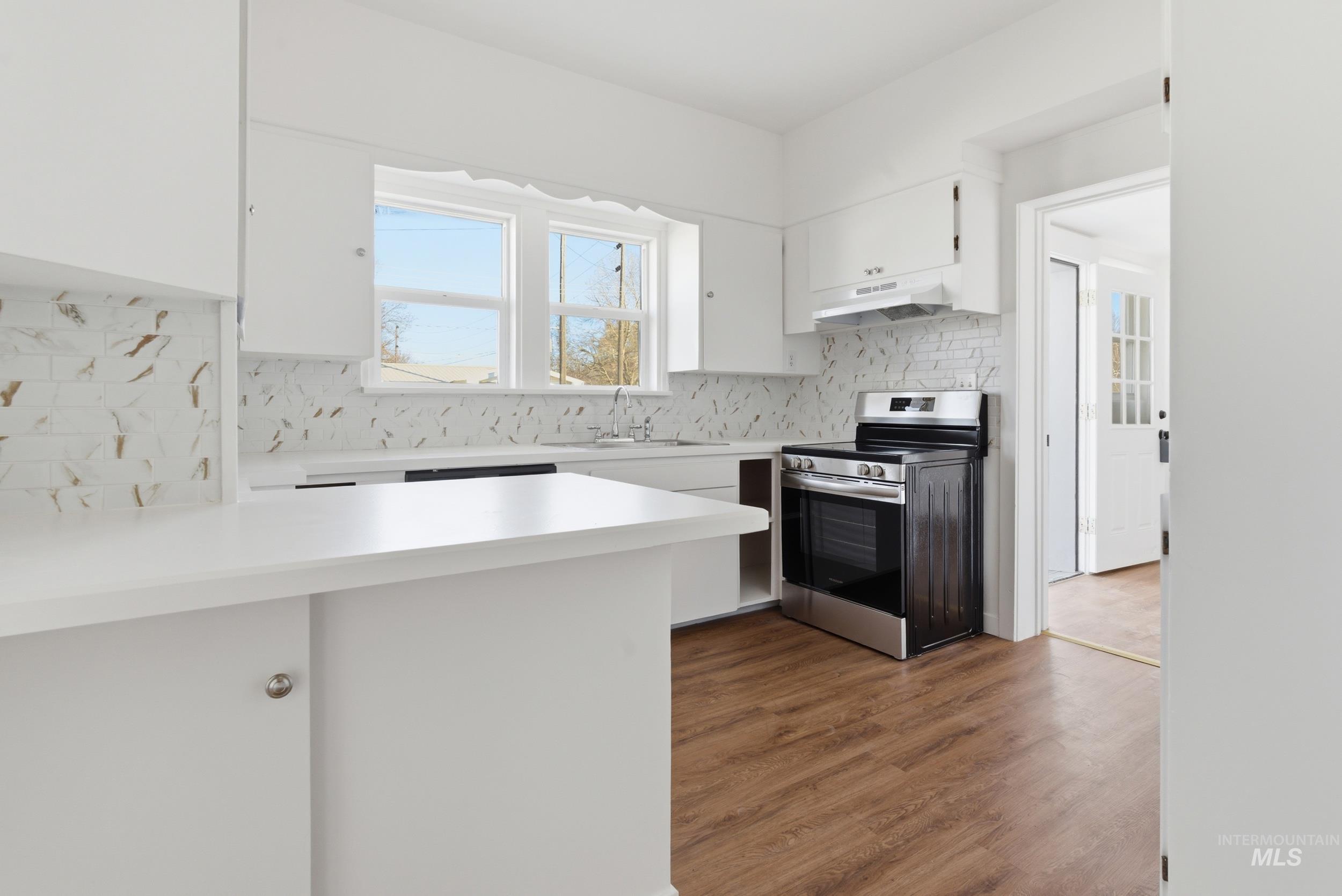 107 West Main Street Declo, ID 83323 - Photo 3 of 32 Kitchen featuring white cabinetry, light countertops, stainless steel range with electric stovetop, a peninsula, and dark wood-style floors