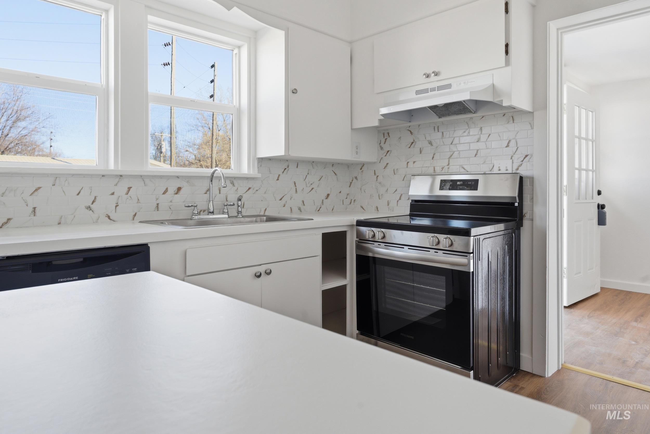 107 West Main Street Declo, ID 83323 - Photo 6 of 32 Kitchen with light countertops, electric range, white cabinetry, and wood finished floors