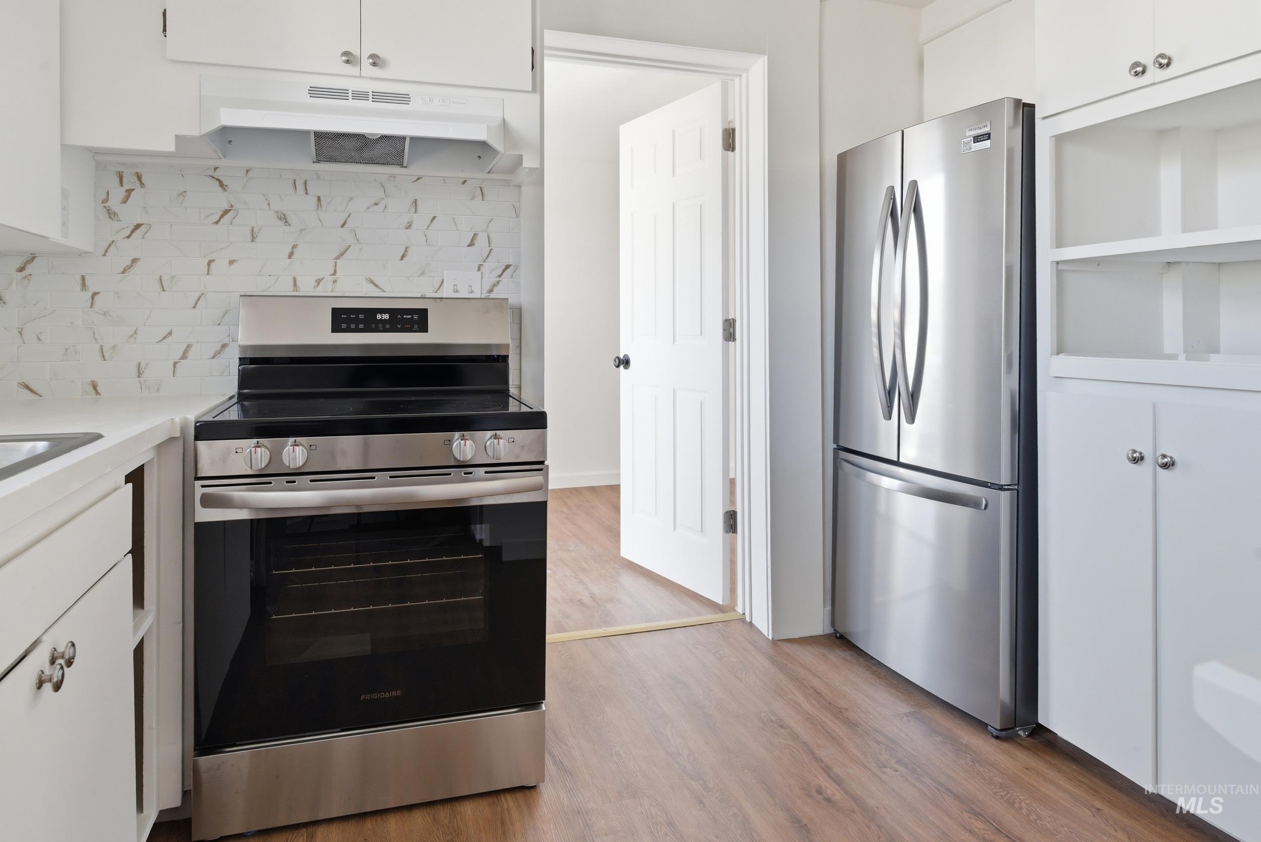 107 West Main Street Declo, ID 83323 - Photo 7 of 32 Kitchen with white cabinets, stainless steel appliances, light wood-style floors, and backsplash