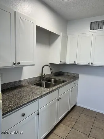 a kitchen with granite countertop white cabinets and sink